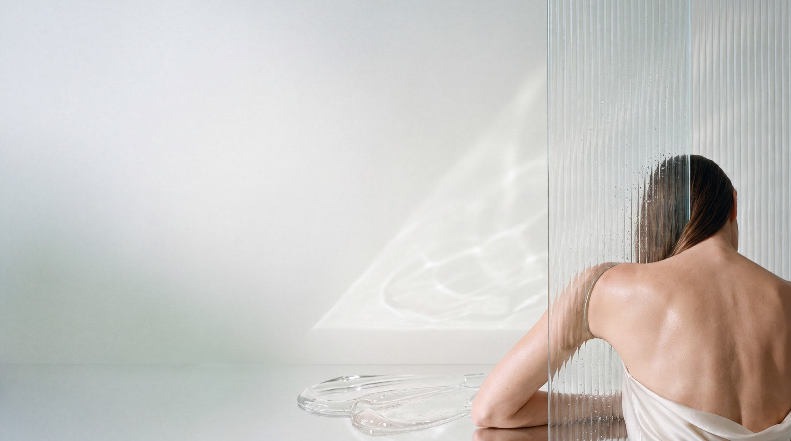 A clear glass sphere resting on stacked glass dishes, under moving water light.